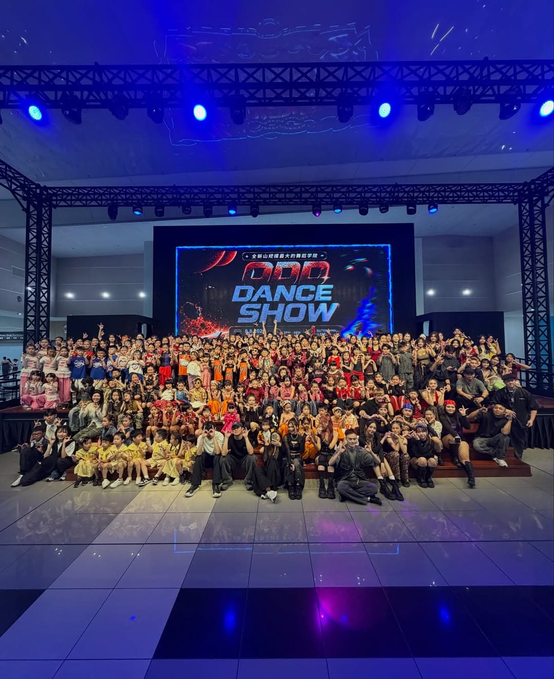 The ODD Dance Show community gathered on stage under blue lights